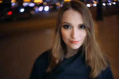 Şehir ışıklarının arkasındaki kızın gece portresi. Deride lear ışığı