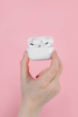 Hava kapsülleri uzmanı. Kablosuz şarj davasıyla. Pembe arka planda New Airpods profesyoneli. Hava kapsülü. Kadın kulaklıkları. Elinde kablosuz kulaklık var.