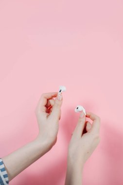 Hava kapsülleri uzmanı. Kablosuz şarj davasıyla. Pembe arka planda New Airpods profesyoneli. Hava kapsülü. Kadın kulaklıkları. Elinde kablosuz kulaklık var.