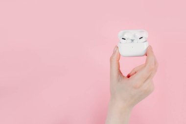 Hava kapsülleri uzmanı. Kablosuz şarj davasıyla. Pembe arka planda New Airpods profesyoneli. Hava kapsülü. Kadın kulaklıkları. Elinde kablosuz kulaklık var.