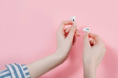 Hava kapsülleri uzmanı. Kablosuz şarj davasıyla. Pembe arka planda New Airpods profesyoneli. Hava kapsülü. Kadın kulaklıkları. Elinde kablosuz kulaklık var.