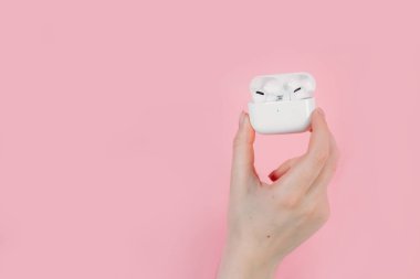 Hava kapsülleri uzmanı. Kablosuz şarj davasıyla. Pembe arka planda New Airpods profesyoneli. Hava kapsülü. Kadın kulaklıkları. Elinde kablosuz kulaklık var.
