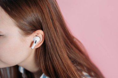 Kız kablosuz kulaklıkla müziği değiştiriyor. Hava kapsülleri uzmanı. Kablosuz şarj davasıyla. Pembe arka planda New Airpods profesyoneli. Hava kapsülü. Kadın kulaklıkları. Boşluğu Kopyala