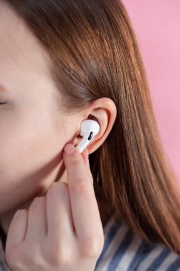 Kız kablosuz kulaklıkla müziği değiştiriyor. Hava kapsülleri uzmanı. Kablosuz şarj davasıyla. Pembe arka planda New Airpods profesyoneli. Hava kapsülü. Kadın kulaklıkları. Boşluğu Kopyala