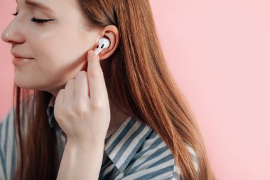 Kız kablosuz kulaklıkla müziği değiştiriyor. Hava kapsülleri uzmanı. Kablosuz şarj davasıyla. Pembe arka planda New Airpods profesyoneli. Hava kapsülü. Kadın kulaklıkları. Boşluğu Kopyala