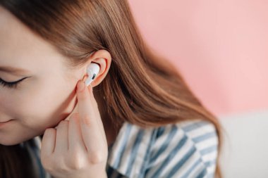 Kız kablosuz kulaklıkla müziği değiştiriyor. Hava kapsülleri uzmanı. Kablosuz şarj davasıyla. Pembe arka planda New Airpods profesyoneli. Hava kapsülü. Kadın kulaklıkları. Boşluğu Kopyala