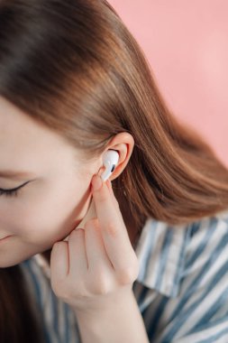 Kız kablosuz kulaklıkla müziği değiştiriyor. Hava kapsülleri uzmanı. Kablosuz şarj davasıyla. Pembe arka planda New Airpods profesyoneli. Hava kapsülü. Kadın kulaklıkları. Boşluğu Kopyala