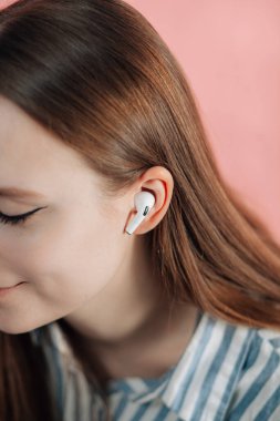 Kız kablosuz kulaklıkla müziği değiştiriyor. Hava kapsülleri uzmanı. Kablosuz şarj davasıyla. Pembe arka planda New Airpods profesyoneli. Hava kapsülü. Kadın kulaklıkları. Boşluğu Kopyala