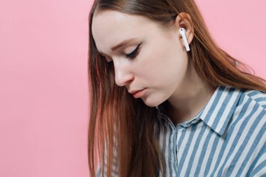 girl on a pink background with a white wireless headphone. Air Pods. with Wireless Charging Case. New Airpods 2019 on pink background. Airpods. female headphones. Copy Space clipart