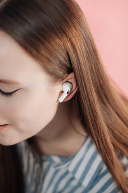 Kız kablosuz kulaklıkla müziği değiştiriyor. Hava kapsülleri uzmanı. Kablosuz şarj davasıyla. Pembe arka planda New Airpods profesyoneli. Hava kapsülü. Kadın kulaklıkları. Boşluğu Kopyala