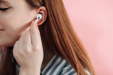 Kız kablosuz kulaklıkla müziği değiştiriyor. Hava kapsülleri uzmanı. Kablosuz şarj davasıyla. Pembe arka planda New Airpods profesyoneli. Hava kapsülü. Kadın kulaklıkları. Boşluğu Kopyala