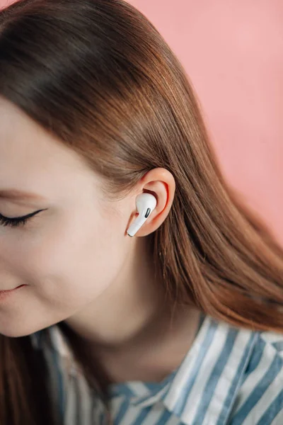 girl switches music on wireless headphones. Air Pods pro. with Wireless Charging Case. New Airpods  pro on pink background. Airpodspro. female headphones. Copy Space