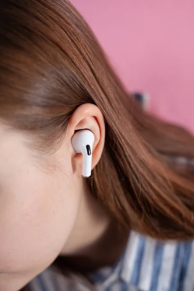 girl switches music on wireless headphones. Air Pods pro. with Wireless Charging Case. New Airpods  pro on pink background. Airpodspro. female headphones. Copy Space