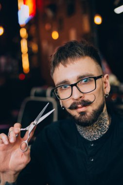 İyi giyimli bir hippi. Berber dükkanı konsepti. Güzellik endüstrisi. Yüz bakımı. Uzun sakallı ve bıyıklı, olgun sakallı hippi. Bıyık stili. Bıyık bırakıyorsun. Bıyık stili.