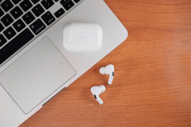 Hava Modülleri Pro. Macbook. Kablosuz şarj davasıyla. Ahşap arka planda yeni hava araçları profesyoneli. Hava podları. Boşluğu kopyala,