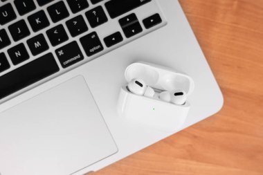 Hava Modülleri Pro. Macbook. Kablosuz şarj davasıyla. Ahşap arka planda yeni hava araçları profesyoneli. Hava podları. Boşluğu kopyala,