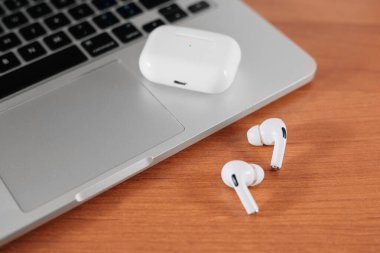 Hava Modülleri Pro. Macbook. Kablosuz şarj davasıyla. Ahşap arka planda yeni hava araçları profesyoneli. Hava podları. Boşluğu kopyala,