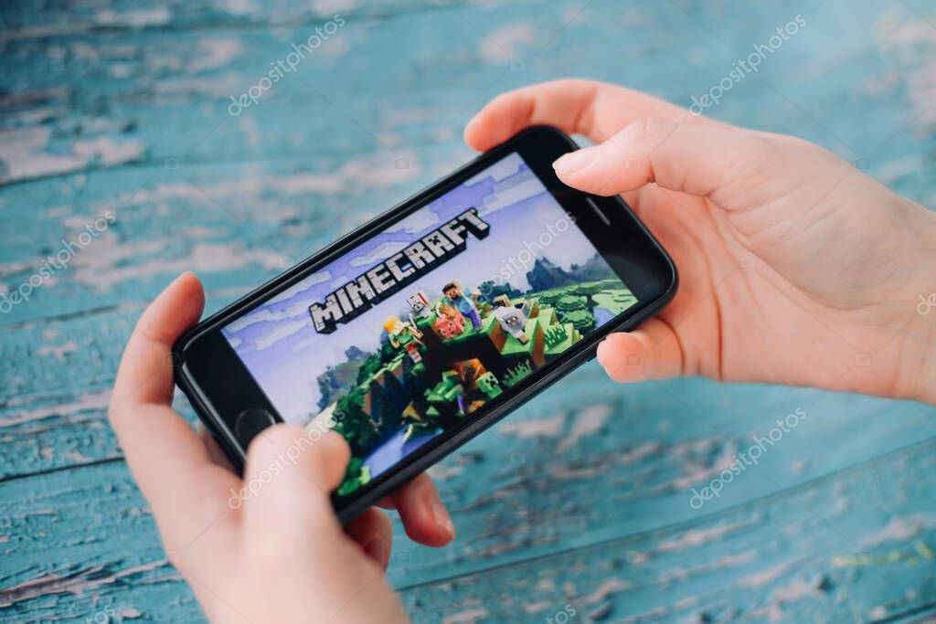 SAINT PETERSBURG, RUSSIA - MAY 27, 2020: Hands holding a smartphone with Minecraft Pocket Edition game on display screen, Illustrative Editorial.