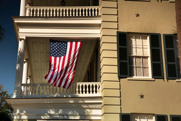 USA flag hangs from a front porch in the summer at a patriotic home in the USA