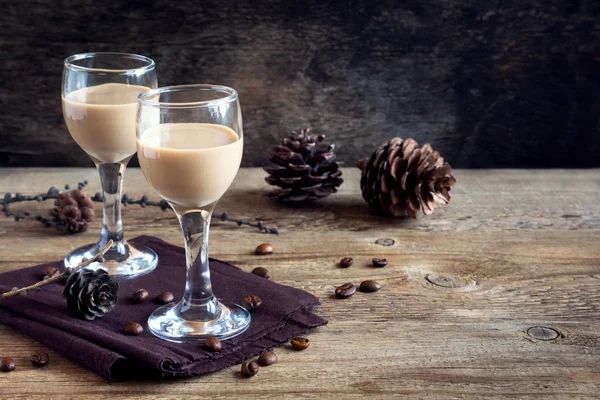 Irish cream coffee liqueur with coffee beans, Christmas decoration and cones over rustic wooden background - homemade festive Christmas alcoholic drink