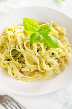 Pesto sos, peynir ve fesleğen ile tagliatelle makarna beyaz tabakta sağlıklı ev yapımı makarna-yakın bırakır