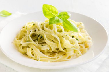 Pesto sos, peynir ve fesleğen ile tagliatelle makarna beyaz tabakta sağlıklı ev yapımı makarna-yakın bırakır