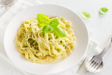 Pesto sos, peynir ve fesleğen ile tagliatelle makarna beyaz tabakta sağlıklı ev yapımı makarna-yakın bırakır