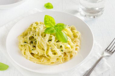 Pesto sos, peynir ve fesleğen ile tagliatelle makarna beyaz tabakta sağlıklı ev yapımı makarna-yakın bırakır