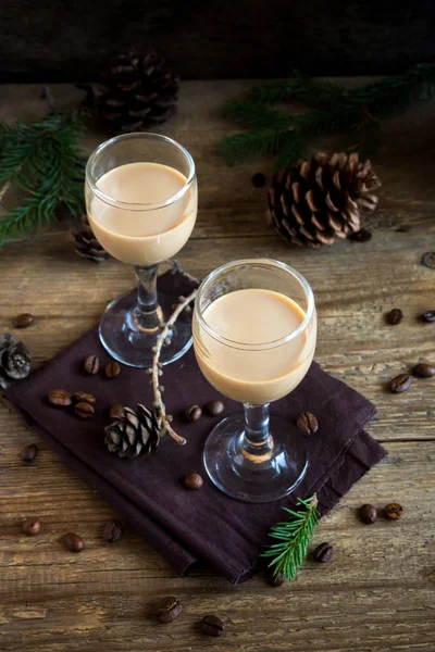 Irish cream coffee liqueur with coffee beans, Christmas decoration and cones over rustic wooden background - homemade festive Christmas alcoholic drink