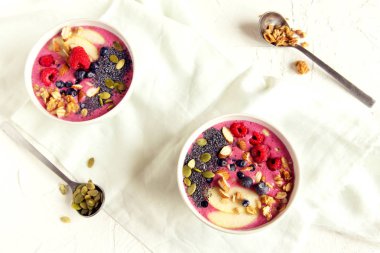 Taze meyveler, fındık, tohumlar ve sağlıklı kahvaltı için ev yapımı granola ile güler yüzlü kase