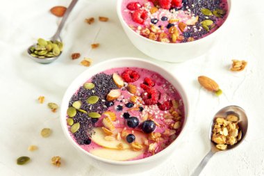 Taze meyveler, fındık, tohumlar ve sağlıklı kahvaltı için ev yapımı granola ile güler yüzlü kase