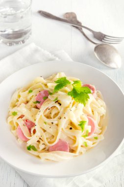 Alfredo tagliatelle makarna sosis ve yeşillik beyaz tabakta - ev yapımı krem makarna ile