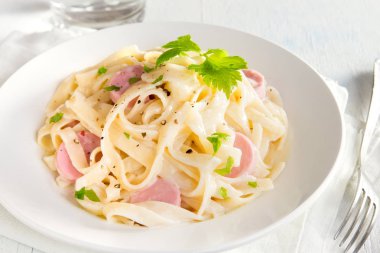 Alfredo tagliatelle makarna sosis ve yeşillik beyaz tabakta - ev yapımı krem makarna ile
