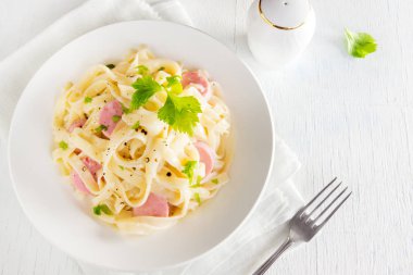 Alfredo tagliatelle makarna sosis ve yeşillik beyaz tabakta - ev yapımı krem makarna ile