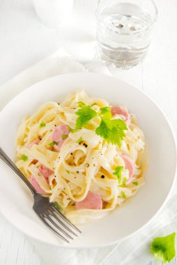 Alfredo tagliatelle makarna sosis ve yeşillik beyaz tabakta - ev yapımı krem makarna ile