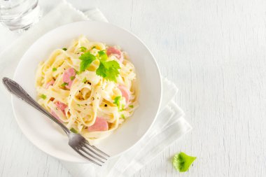 Alfredo tagliatelle makarna sosis ve yeşillik beyaz tabakta - ev yapımı krem makarna ile