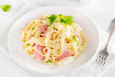 Alfredo tagliatelle makarna sosis ve yeşillik beyaz tabakta - ev yapımı krem makarna ile