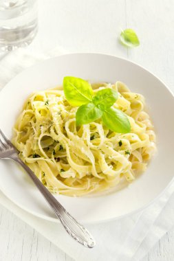 Pesto sos, peynir ve fesleğen ile tagliatelle makarna beyaz tabakta sağlıklı ev yapımı makarna-yakın bırakır