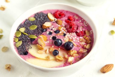 Sağlıklı vejetaryen diyeti kahvaltısı için taze böğürtlen, fındık, tohum ve ev yapımı granola ile meyve suyu kasesi.