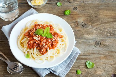 Spagetti bolognese makarna salça ve kıyma, rendelenmiş parmesan peyniri ve taze fesleğen - kopya alanı rustik ahşap zemin üzerine ev yapımı sağlıklı İtalyan Makarna