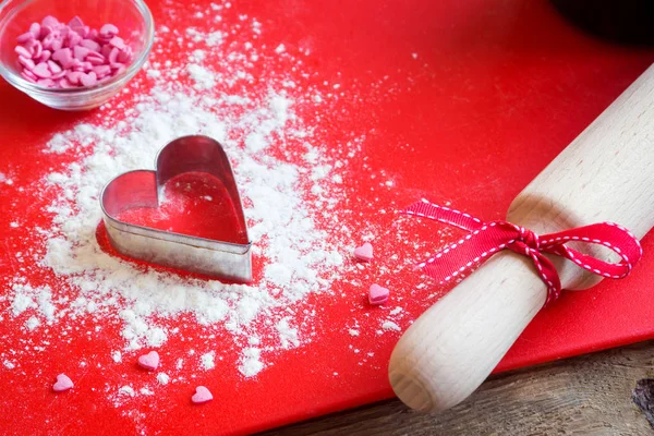 ハート形のクッキーのカッター 小麦粉 コピー スペース ロマンス バレンタインの日お祝いの自家製ペストリー概念を焼くと木と赤い背景の上のローラー — ストック写真