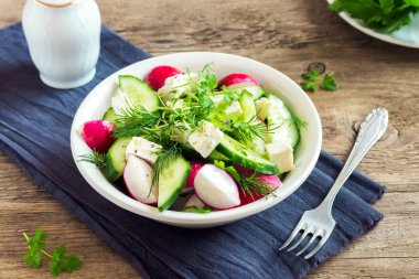 Taze salatalık, turp, beyaz peynir, otlar bahar salatası, vegan vejetaryen salata yemek lahanası kase üzerinde ahşap arka plan - sağlıklı detoks diyet