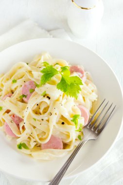 Alfredo tagliatelle makarna sosis, krem sos ve Yeşiller beyaz tabakta - ev yapımı krem makarna ile