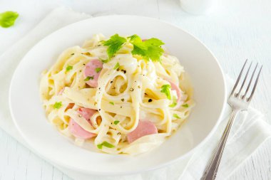 Beyaz tabakta - sağlıklı ev yapımı makarna tagliatelle makarna pesto sos, peynir ve fesleğen yaprakları