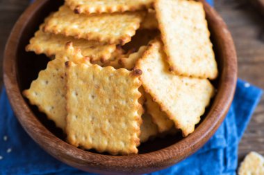 Kırsal ahşap kasede susam tohumlu ev yapımı ince çıtır peynirli krakerler. Taze organik ev yapımı peynirli krakerler.