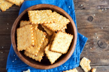 Kırsal ahşap kasede susam tohumlu ev yapımı ince çıtır peynirli krakerler. Taze organik ev yapımı peynirli krakerler.