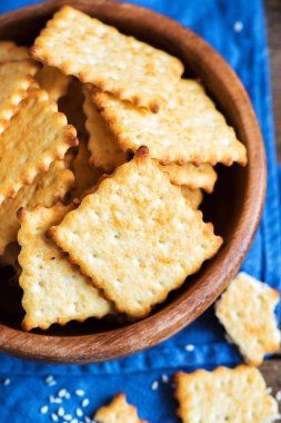 Kırsal ahşap kasede susam tohumlu ev yapımı ince çıtır peynirli krakerler. Taze organik ev yapımı peynirli krakerler.