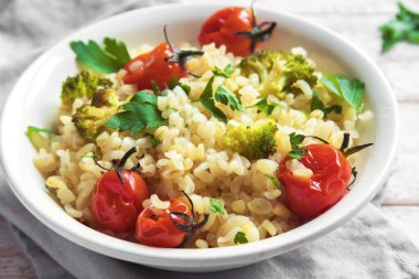 Sebzeli bulgur: domates, brokoli ve beyaz ahşap arka plan - sağlıklı ev yapımı organik vegan vejetaryen diyet yemek üzerine maydanoz