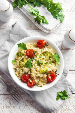 Sebzeli bulgur: domates, brokoli ve beyaz ahşap arka plan - sağlıklı ev yapımı organik vegan vejetaryen diyet yemek üzerine maydanoz