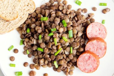 Ev yapımı sosis (cotechino) beyaz tabakta ile yeşil mercimek